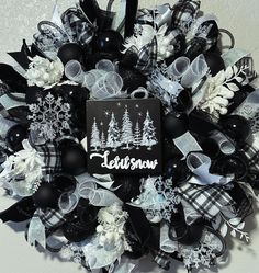 a black and white christmas wreath with snowflakes, pine trees, and ribbons