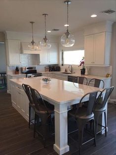 a large kitchen with an island in the middle and chairs at the counter top on the side