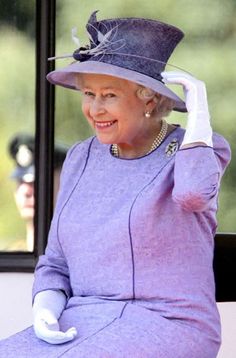 the queen of england is sitting on a bench wearing a purple dress and hat with white gloves