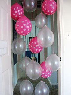 some balloons are hanging from the ceiling in front of an open door with pink and white polka dots on them