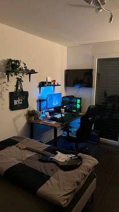 a bedroom with a bed, computer desk and guitar on the wall next to it