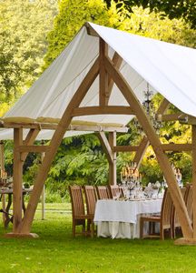 an outdoor dining area with tables, chairs and a tent in the middle of it