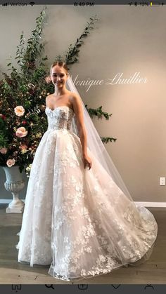 a woman in a wedding dress standing next to flowers