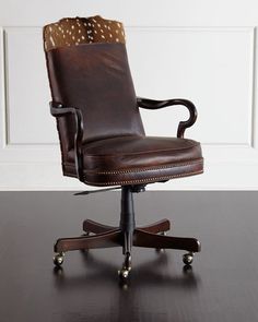 a brown leather office chair sitting on top of a wooden table next to a white wall