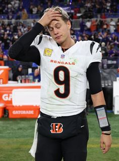 a football player holding his head while standing on the field