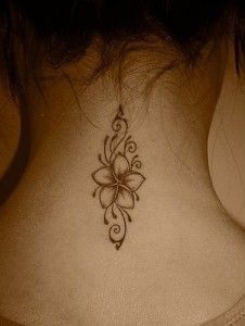 a woman's back neck with a flower tattoo on the upper part of her neck