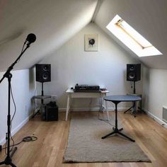 a room with two speakers, a table and a microphone on the floor in front of it