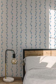 a bed sitting under a window next to a wall with blue vines painted on it