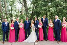 a group of people standing next to each other in front of some trees and bushes