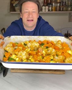 a man sitting at a table with a pan full of food