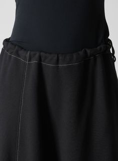 the back view of a woman's black skirt with white stitching on it