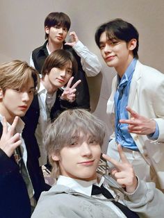 the group of young men are posing together for a photo with their fingers in the air