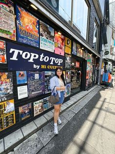 a woman is standing in front of a wall with posters on it and the words top to top by lil culp