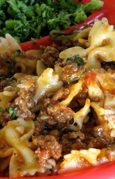 a red basket filled with pasta and meat covered in sauce