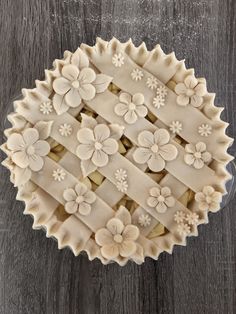 a pie with flowers on it sitting on top of a wooden table