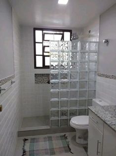 a bathroom with a toilet, sink and glass block wall in the shower stall area