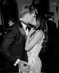 a man in a tuxedo kisses a woman's face as they stand next to each other