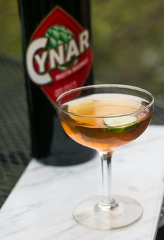 a close up of a wine glass on a table with a bottle in the background