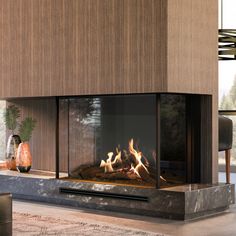 a modern fireplace in the middle of a living room with wood paneling and glass doors