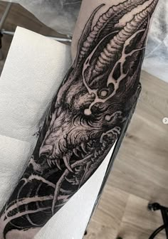 a man's arm with a black and white dragon tattoo on the left forearm