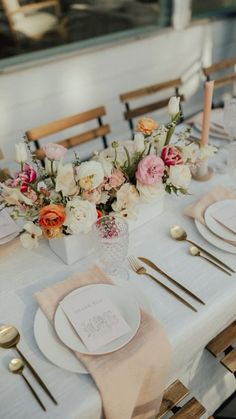 the table is set with white and pink flowers