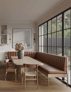 a dining room table and bench with flowers in a vase on it's centerpiece