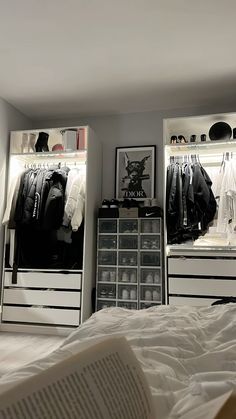 an open book is sitting on the bed in front of two closets with clothes and shoes