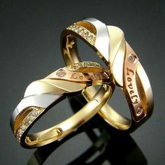 two gold and silver wedding rings with diamonds on each band, set against a black background