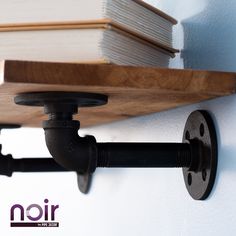 a close up of a book shelf with books on it and a pipe running down the wall