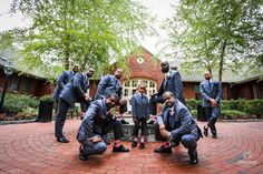 a group of men in suits and ties posing for a photo on a brick walkway