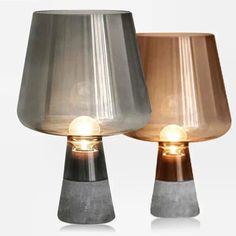 two lamps sitting next to each other on top of a white surface with one light turned on