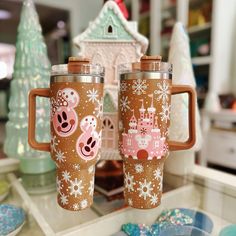 two coffee mugs with mickey mouse designs on them are sitting on a counter top