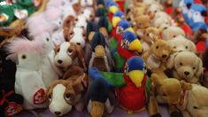 many stuffed animals are lined up together on the table in front of other stuffed animals