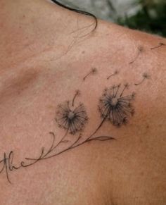 a tattoo on the back of a man's shoulder with dandelions in it