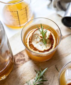 three glasses filled with different types of drinks on top of a wooden table next to measuring cups