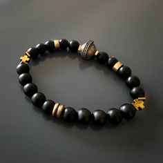 The Black Vibe Onyx Stone Beaded Gladiator Bracelet is more than just a piece of jewelry—it's a symbol of strength and confidence. The combination of black onyx stones and gold hematite beads creates a striking contrast that adds depth and dimension to the handmade bracelet. Black onyx is known for its protective qualities and is believed to absorb negative energy, while gold hematite is associated with grounding and stability. The gladiator charm serves as a reminder of the warrior within, symb Spiritual Hand-strung Black Bracelets, Spiritual Black Hand-strung Bracelets, Spiritual Black Hand-strung Bracelet, Spiritual Black Polished Beaded Bracelets, Black Spiritual Beaded Bracelets With Polished Beads, Handmade Onyx Black Bracelets, Spiritual Black Polished Beads Bracelet, Handmade Black Onyx Bracelets, Handmade Symbolic Black Beaded Bracelets