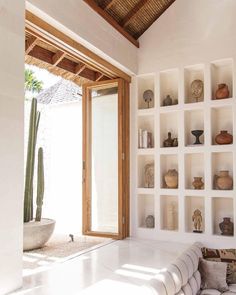 a living room filled with lots of white furniture and shelves next to a cactus plant