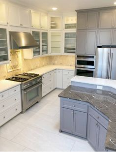 a kitchen with marble counter tops and stainless steel appliances, along with white cabinetry