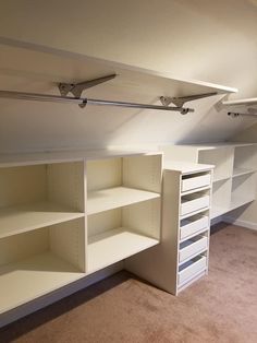 an empty room with white shelving and shelves in the corner, along with carpeted flooring