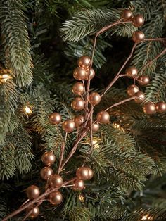 the branches of a christmas tree are covered with gold balls and garland lights, as well as green needles