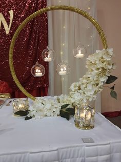 white flowers and candles on a table with a circular mirror in the background at a wedding reception