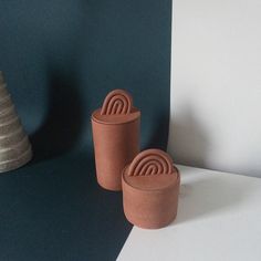 two clay pots sitting next to each other on a white counter top in front of a blue wall