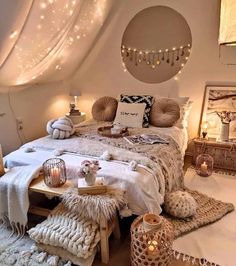 a bedroom decorated in white with lights on the ceiling and blankets, pillows, rugs and other decorations