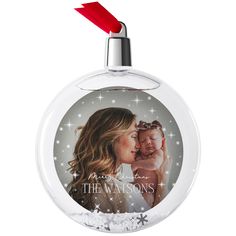 a christmas ornament with a woman holding a baby in her arms and snowflakes around it