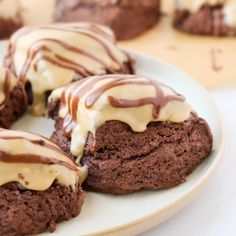 chocolate cookies covered in white frosting and drizzled with icing on a plate