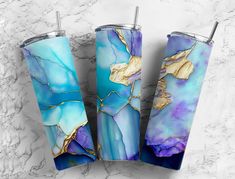 three blue and gold tumblers sitting on top of a marble counter next to each other