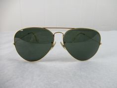 "Vintage 1960s Ray Ban sunglasses. Gold frame with green glass non prescription lenses. Marked: RAY BAN B & L U.S.A. 62 [] 14. Sunglasses measure: 5.5\" across the front and each temple is 5\" long. Each lens is 62mm across. In very good condition with a tiny mark on the right lens(photo)." Retro Green Aviator Sunglasses With Tinted Lenses, Retro Green Tinted Aviator Sunglasses, Vintage Summer Aviator Sunglasses, Vintage Aviator Sunglasses With Mirrored Lenses, Vintage Aviator Sunglasses With Tinted Lenses, Vintage Aviator Sunglasses With Polarized Lenses For Summer, Vintage Green Sunglasses With Gradient Lenses, Green Vintage Sunglasses With Tinted Lenses, Green Vintage Sunglasses With Gradient Lenses