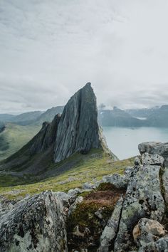 a large rock outcropping on top of a mountain with water in the background