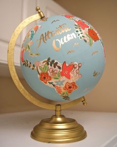 a blue and gold globe with flowers on it is hanging from a hook in a room