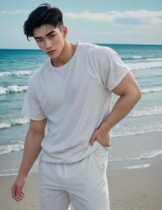 a man standing on top of a sandy beach next to the ocean with his hands in his pockets